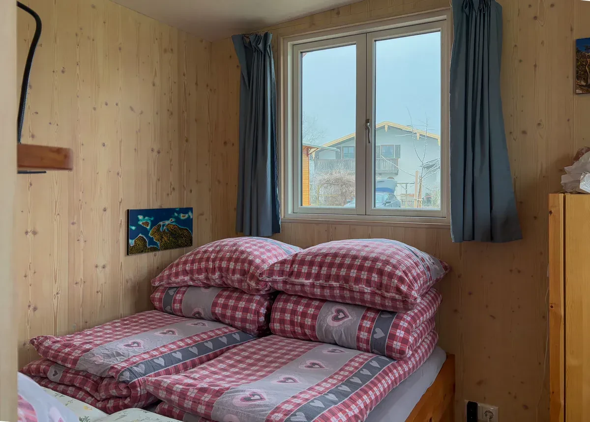 A simple, tidy tiny cabin interior with wood walls and natural light, the kind of small off-grid space a composting toilet is built for